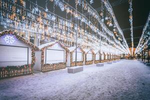 Navidad o nuevo años mercado en un Europa con casas decorado con juguete pelotas y guirnaldas a noche. Clásico película estético. foto