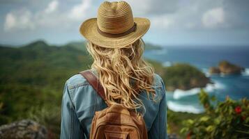 A woman stands with a backpack, gazing at the vast ocean photo