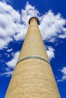 The minaret of a brick mosque against a cloudy sky. photo