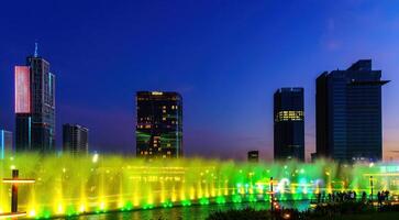 uzbekistán, Tashkent - septiembre 29, 2023 un fuente con láser iluminación y ligero música en Tashkent ciudad parque a Noche y rascacielos. foto