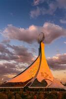 uzbekistán, Tashkent - octubre 4, 2023 Monumento de independencia en el formar de un estela con un humo pájaro en un crepúsculo con cliody cielo en el nuevo Uzbekistán parque. foto