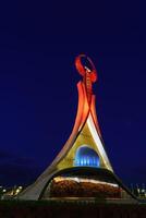 uzbekistán, Tashkent - octubre 4, 2023 iluminado Monumento de independencia en el formar de un estela con un humo pájaro en el nuevo Uzbekistán parque a Noche en otoño. foto