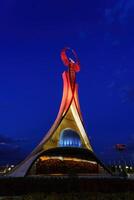 uzbekistán, Tashkent - octubre 4, 2023 iluminado Monumento de independencia en el formar de un estela con un humo pájaro en el nuevo Uzbekistán parque a Noche en otoño. foto