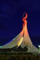 Uzbekistan, Tashkent - October 4, 2023 Illuminated monument of independence in the form of a stele with a Humo bird in the New Uzbekistan park at nighttime in autumn. photo