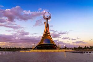 uzbekistán, Tashkent - octubre 4, 2023 Monumento de independencia en el formar de un estela con un humo pájaro en un crepúsculo con cliody cielo en el nuevo Uzbekistán parque. foto