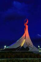 Uzbekistan, Tashkent - October 4, 2023 Illuminated monument of independence in the form of a stele with a Humo bird in the New Uzbekistan park at nighttime in autumn. photo