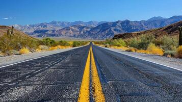 An empty road stretches ahead with towering mountains in the distant background photo