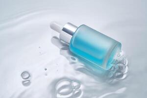 Bottles of cosmetics with a dropper in water on a blue background. photo