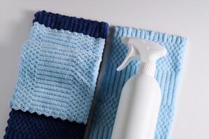 Cleaning product with a sprayer on a background of a blue microfiber cloth. photo