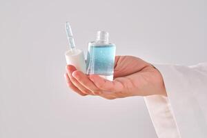 Blue serum with pipette in a womans hands in a robe. photo