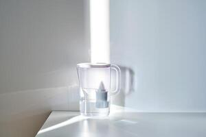 A jug with a water filter in the sun on the table. photo