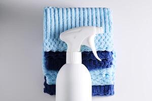 Cleaning product with a sprayer on a background of a blue microfiber cloth. photo