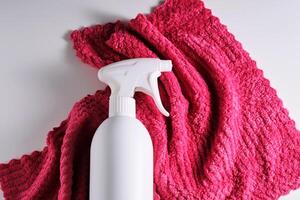 Cleaning product with a sprayer on a background of a red microfiber cloth. photo