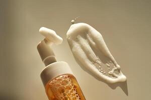 Beige facial foam with a dispenser and brush in the rays of the setting sun. photo