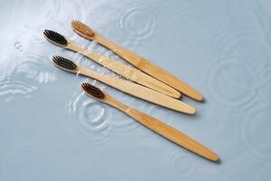 Natural bamboo toothbrushes in water on a blue background. photo