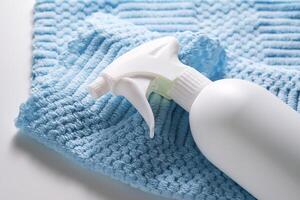Cleaning product with a sprayer on a background of a blue microfiber cloth. photo
