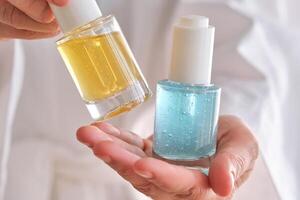 Two yellow and blue serums in a womans hands in a robe. photo