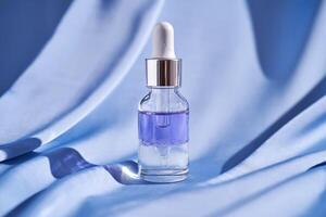 Two-component facial serum on a blue silk background. photo