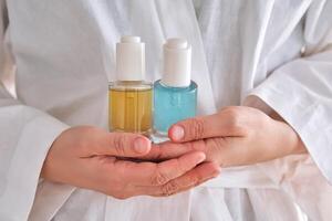 Two yellow and blue serums in a womans hands in a robe. photo