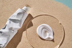 A tube of moisturizing sunscreen and a smear on a sandy background. photo