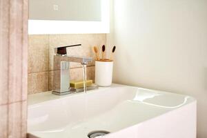 Bathroom sink with toothbrushes and running water. photo