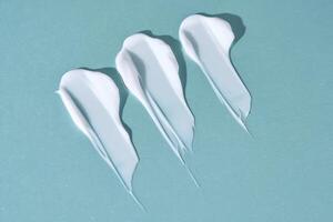 Three strokes of white cream on a blue background. photo