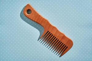 Wooden comb on a pink polka dot background. photo