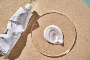 A tube of moisturizing sunscreen and a smear on a sandy background. photo