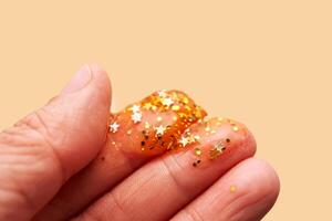 Cosmetic gel with glitter on women's fingers on a beige background. photo