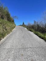 Empty asphalt road on the Camino del Norte in Spain leading up a hill on a sunny day photo