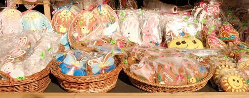 Traditional Easter gingerbread cookies in the shape of a colorful egg with drawings of a hare and chickens are sold at a market photo