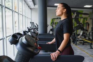 atractivo joven Deportes mujer es trabajando fuera en gimnasia. haciendo cardio formación en rueda de andar. corriendo en rueda de andar foto