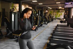 Young woman drinking water and taking a break after workout in gym photo