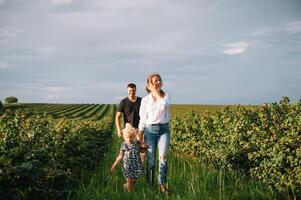 contento familia con pequeño hija gasto hora juntos en soleado campo. foto