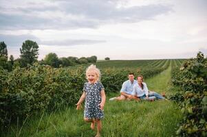 contento familia con pequeño hija gasto hora juntos en soleado campo foto