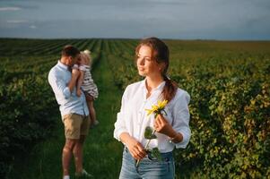 contento familia con pequeño hija gasto hora juntos en soleado campo. foto