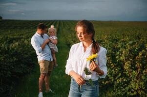 contento familia con pequeño hija gasto hora juntos en soleado campo. foto