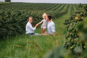 Happy family walking in the park. Mom, dad and daughter walk outdoors, parents holding the baby girl's hands. Childhood, parenthood, family bonds, marriage concept. photo