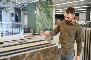 Man choosing tile among different samples in store photo