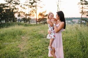 elegante madre y hermoso hija teniendo divertido en el naturaleza. contento familia concepto. belleza naturaleza escena con familia al aire libre estilo de vida. familia descansando juntos. felicidad en familia vida. madres día. foto