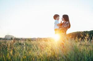 elegante madre y hermoso hijo teniendo divertido en el naturaleza. contento familia concepto. belleza naturaleza escena con familia al aire libre estilo de vida. contento familia descansando juntos. felicidad en familia vida. madres día foto