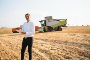 contento granjero en el campo comprobación maíz plantas durante un soleado verano día, agricultura y comida producción concepto. foto