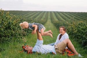 Happy family with little daughter spending time together in sunny field photo