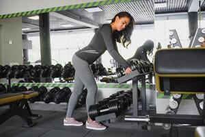 deportivo mujer en gimnasia. mujer levantamiento pesos y trabajando en su cofre a el gimnasia. foto