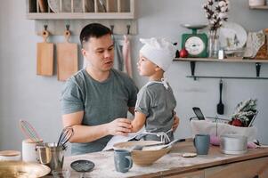 Young man and his son with oven sheet in kitchen. Father with little son on the kitchen photo