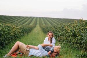 The daughter hugging parents on nature. Mom, dad and girl toddler, walk in the grass. Happy young family spending time together, outside, on vacation, outdoors. The concept of family holiday photo