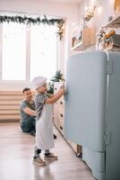 joven hombre y su hijo con horno sábana en cocina. padre con pequeño hijo en el cocina. foto