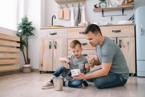 Young man and his son with oven sheet in kitchen. Father with little son on the kitchen. photo