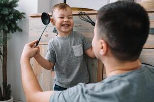 Young man and his son with oven sheet in kitchen. Father with little son on the kitchen photo