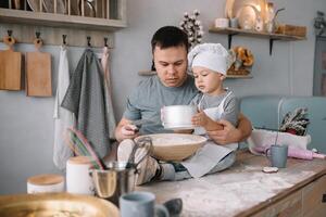 joven hombre y su hijo con horno sábana en cocina. padre con pequeño hijo en el cocina. foto